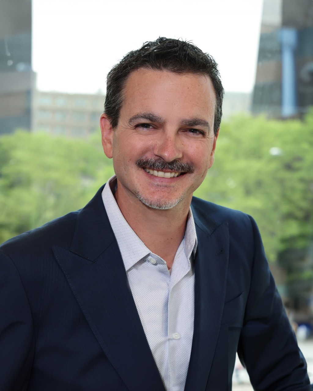 Jeff Cali, Venture One executive, smiling in a business setting with greenery in the background