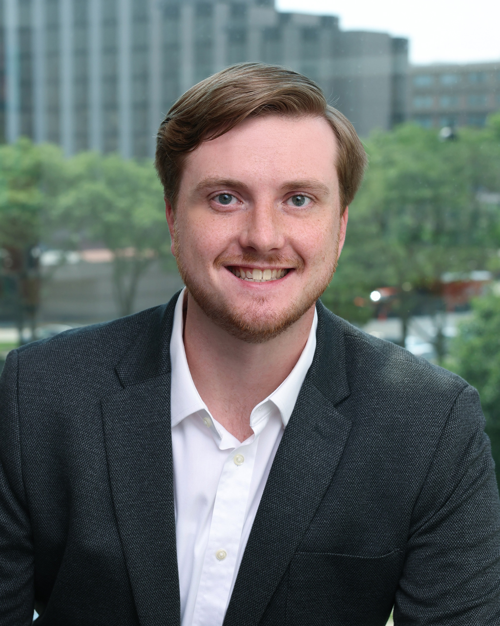 Hayden Monix, a professional in industrial real estate, smiling in an office with a city view.