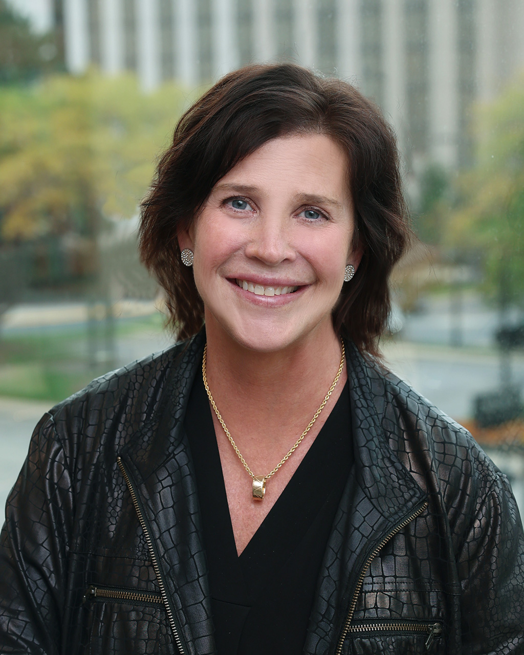 Meg Muldowney, Venture One executive, smiling in a professional setting with a city view.