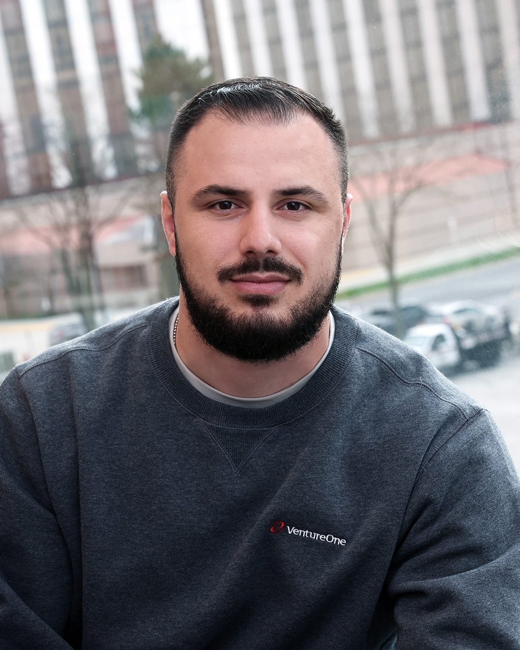 Genc Smajli professional at Venture One posing with city backdrop, team member portrait